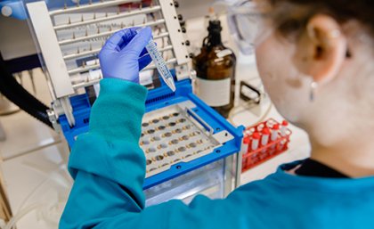 Back of researcher in lab holding up test tube of liquid